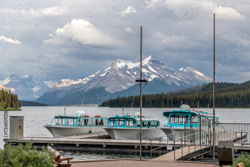 Three passenger tour boats at dock with Mt Charlton and Queen Elizabeth Ranges in the background, Maligne Lake, Jasper National Park, Alberta, Canada