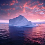 Antarctic iceberg in the snow floating in open ocean. Pink sunset sky in the background.