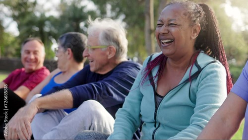 Multiracial group of senior people having fun after exercise yoga workout at park. African woman laughing with friends