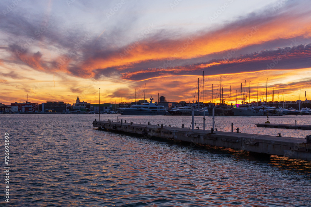 Sunset at the marina with vibrant orange clouds reflecting on the water