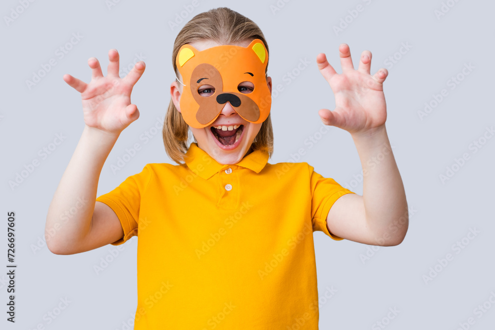 Child wearing bear mask and scare on a gray background. DIY toys, dress up costumes mask, party supplies, birthday party favors, play accessories, photo booth props for kids. High quality photo