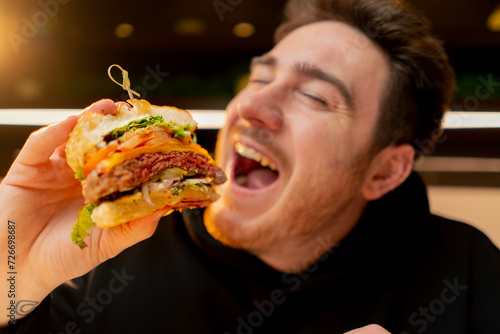 close-up man with enjoy biting delicious juicy cheeseburger in cafe restaurant junk food calories © Guys Who Shoot