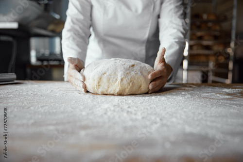 Fotografie Baker hands holding kneaded dough to prepare fresh bread