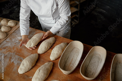 Baker hands preparing formed bread dough for proofing photo