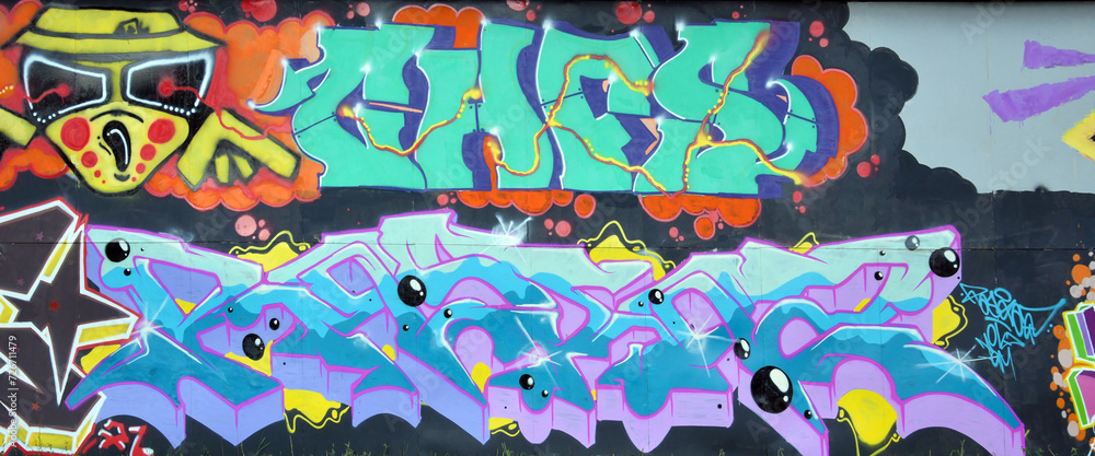 The old wall decorated with paint stains in the style of street art culture. Colorful background of full graffiti painting artwork with bright aerosol outlines on wall. Colored background texture The old wall decorated with paint stains in the style of street art culture. Colorful background of full graffiti painting artwork with bright aerosol outlines on wall. Colored background texture