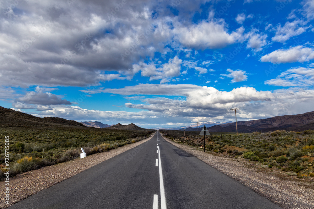 Carretera con un final infinito y bajo un cielo con nubes Carretera con un final infinito y bajo un cielo con nubes