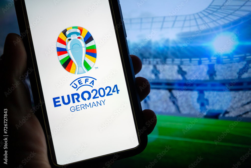 Hand holding a smartphone displaying the UEFA EURO 2024 logo with a ...