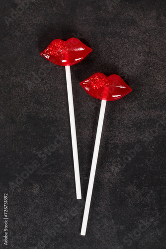 Two Red lips lollipops on a paper stick. Couple. Dark background. Top view. Valentine's day