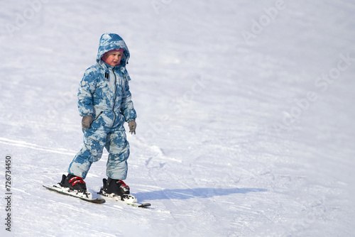 A child learns to ski (balance) on alpine skis. Copy space.