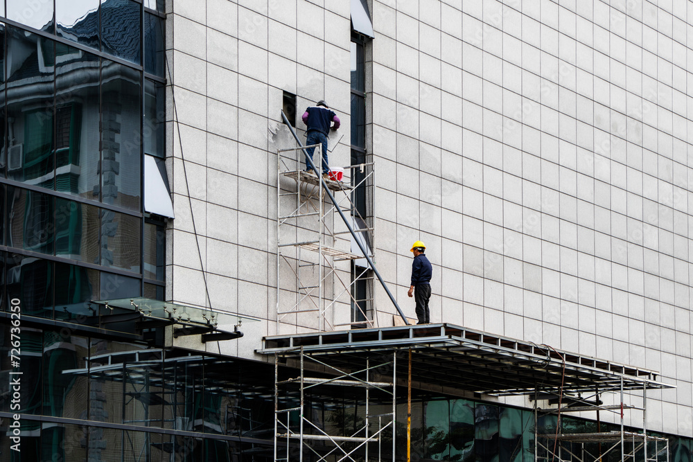 facade installation, men at work, workers install, on a high-rise building. Installation in an office on a construction site. curtain wall systems are new, panel, frame, multilayer, construction.