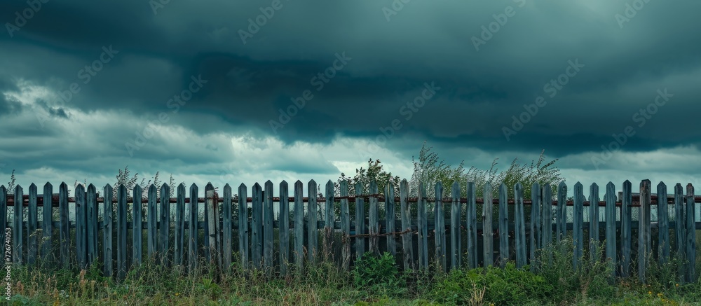 Gloomy clouds appear before rain, revealing a lovely fence.