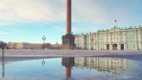 Saint-Petersburg, Russia - Feb 02 2024, a panoramic view of Palace square with mirror puddle, close-up of human legs jumping past, with the Winter palace on background, Saint Petersburg, Russia  photo