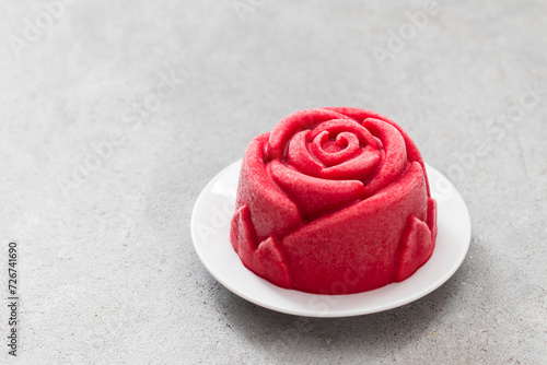 Strawberry sorbet in the shape of a red rose. On a plate. Light grey background. Copy space
