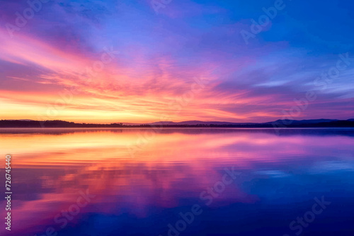 sunrise over a serene lake, with vibrant colors painting the sky