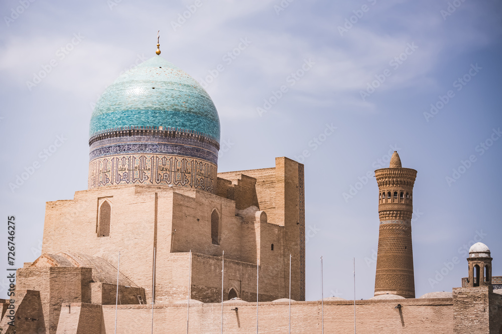 Obraz premium City panorama from the park at the mausoleum of the madrasah and the Kalon Minaret in the ancient city of Bukhara in Uzbekistan on a warm summer sunny day