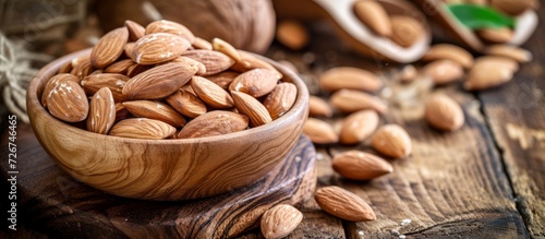 Raw almonds placed on a wooden bowl and acacia cutting board. photo