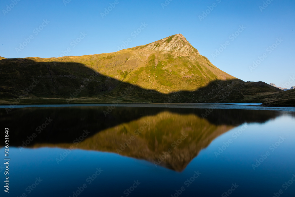 Reflection of a mountain peak in a calm lake at sunrise
