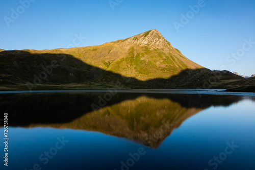Reflection of a mountain peak in a calm lake at sunrise © Carlos Cairo