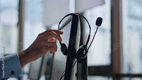 Closeup hand taking headset at call center. Technical support equipment hanging photo
