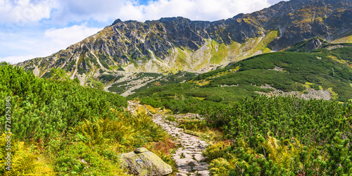 Polish Tatra Mountains, high mountain hiking trail leading to mountain peaks, mountain landscape with valleys and slopes, view on a sunny summer day.
