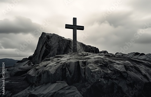 A stark black and white landscape featuring a Christian cross atop a rugged mountain under a dramatic, cloudy sky.