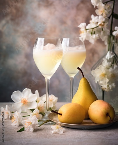  a plate topped with two pears next to two glasses of white wine and a vase with white flowers behind it.