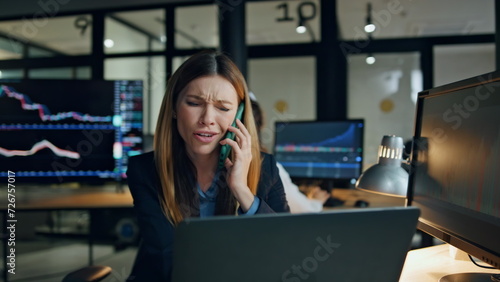 Annoyed businesswoman talking smartphone at workplace. Nervous stock trader work