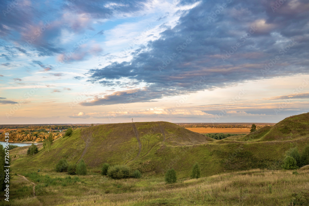 View of a hill in the countryside, evening landscape with sunset sky