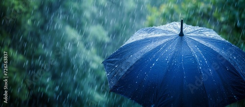 Blue umbrella in heavy rain against a natural backdrop represents the concept of rainy weather. photo