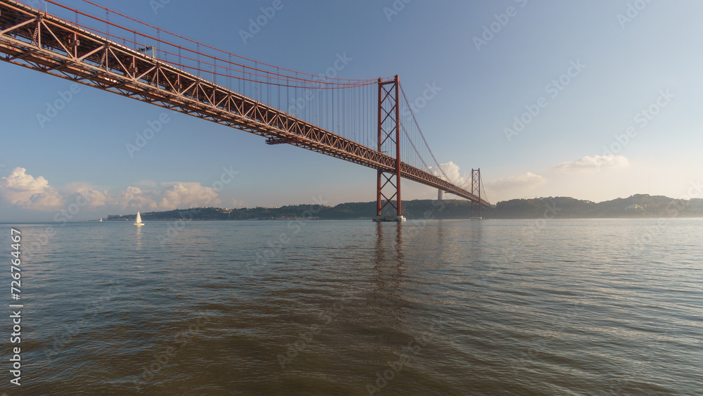 Red bridge 25 de Abril Bridge and statue of Cristo Rei during a slightly misty day, Lisbon, Portugal