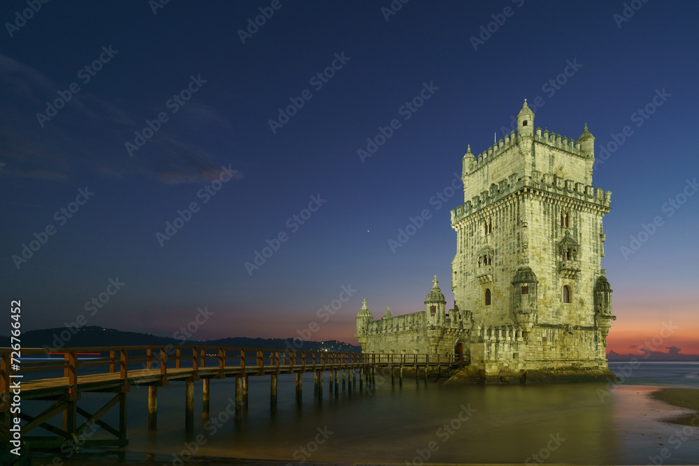 Illuminated Torre de Belem during evening twilight after sunset with planets Venus and Saturn on the sky, Lisbon, Portugal