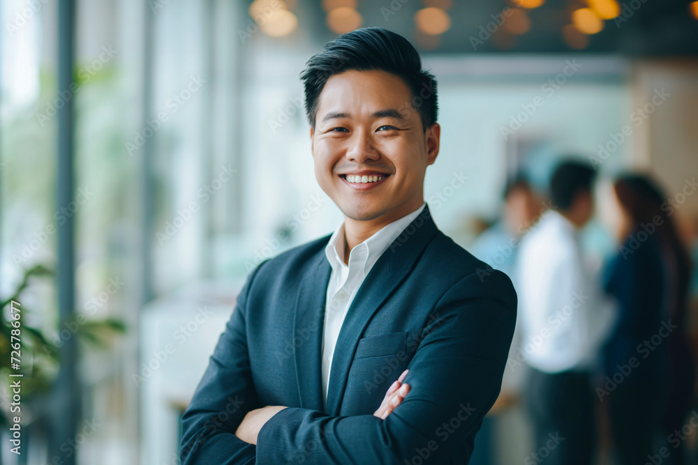 Portrait of a handsome smiling Asian businessman boss in a suit standing in a modern business company office Portrait of a handsome smiling Asian businessman boss in a suit standing in a modern business company office