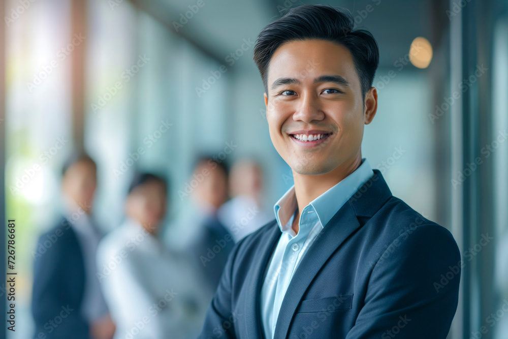 Portrait of a handsome smiling Asian businessman boss in a suit standing in a modern business company office Portrait of a handsome smiling Asian businessman boss in a suit standing in a modern business company office