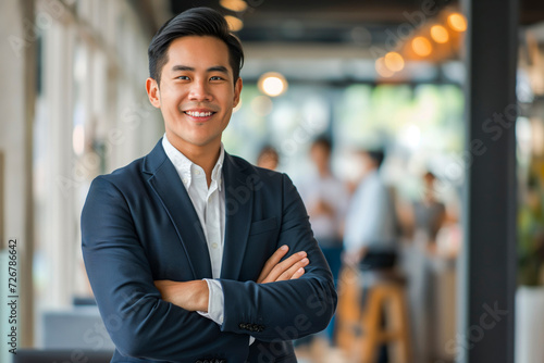 Portrait of a handsome smiling Asian businessman boss in a suit standing in a modern business company office
