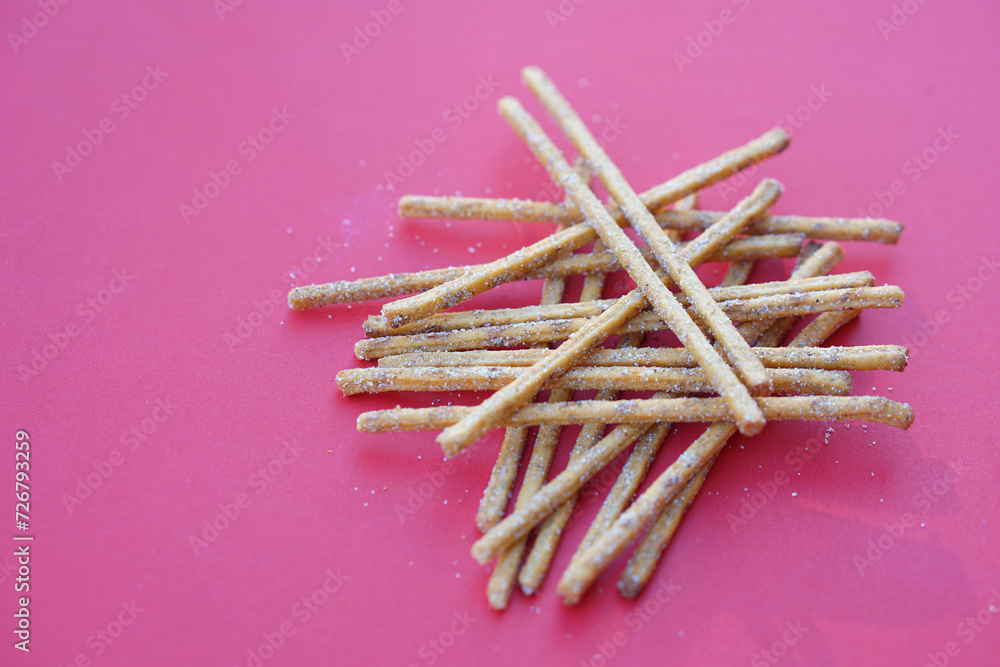 Crunchy salty and spicy flavored pretzel sticks, breadsticks, snacks on red background. Concept, junk food, appetizer. Crunchy salty and spicy flavored pretzel sticks, breadsticks, snacks on red background. Concept, junk food, appetizer.