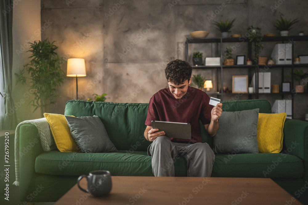 teenager young man sit at home use credit card shopping online