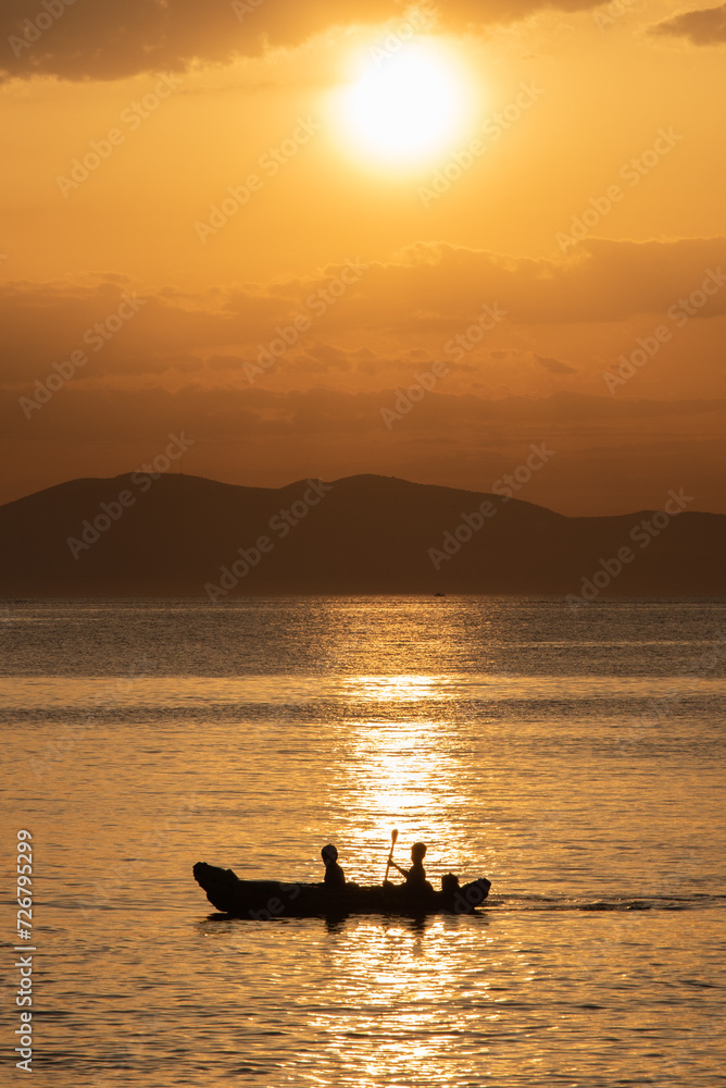 A boat with two people into the golden sunset