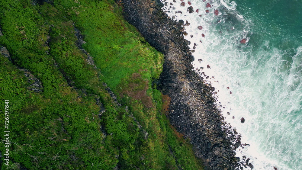 Ocean surf splashing mossy cliffs nature drone top view. Foaming waves beach
