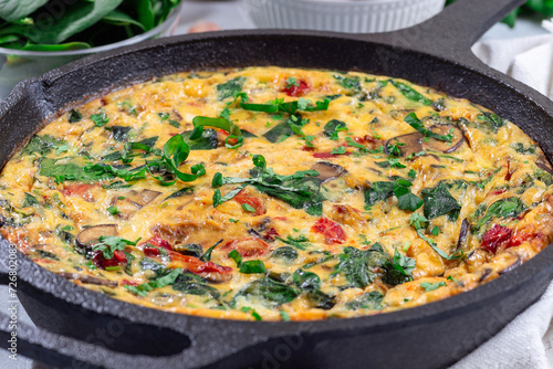 Egg frittata with spinach, roasted peppers, mushrooms, cheese, in cast iron, horizontal, closeup