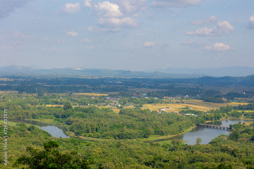 Fototapeta premium Overview from Wat Phra That Doi Prachan with small town villages, farmland and forest, Mae Chang river or canal with bridge, Located in the district of Mae Tha District, Lampang, Northern of Thailand.