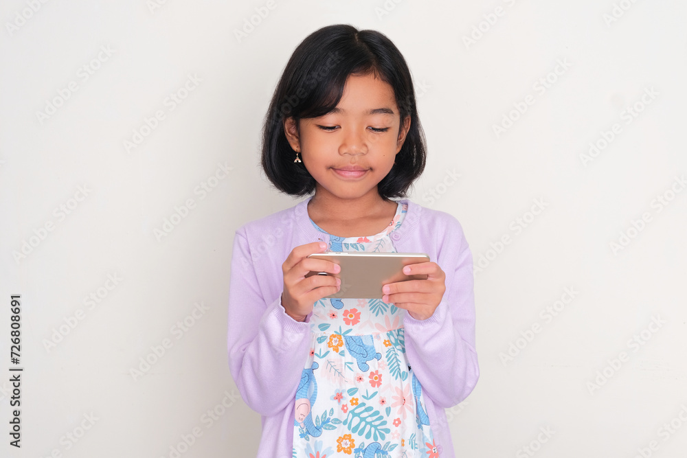 Asian kid smiling when looking to her cellphone Asian kid smiling when looking to her cellphone