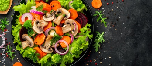 Beautiful salad with mushrooms, lettuce, carrots, beet leaves, and red onion rings, viewed from the top.