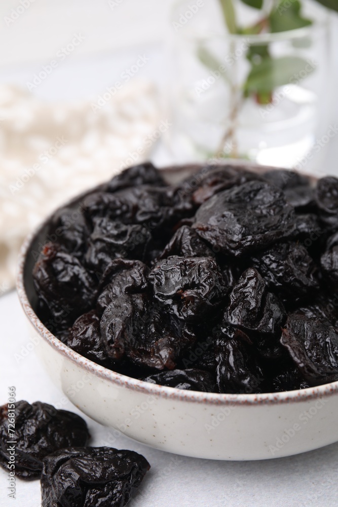 Bowl with sweet dried prunes on light table, closeup Bowl with sweet dried prunes on light table, closeup