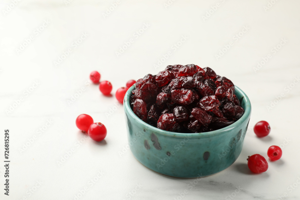 Tasty dried cranberries in bowl and fresh ones on white marble table, closeup. Space for text Tasty dried cranberries in bowl and fresh ones on white marble table, closeup. Space for text