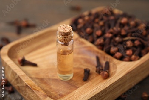 Clove oil in bottle and dried buds on table, closeup