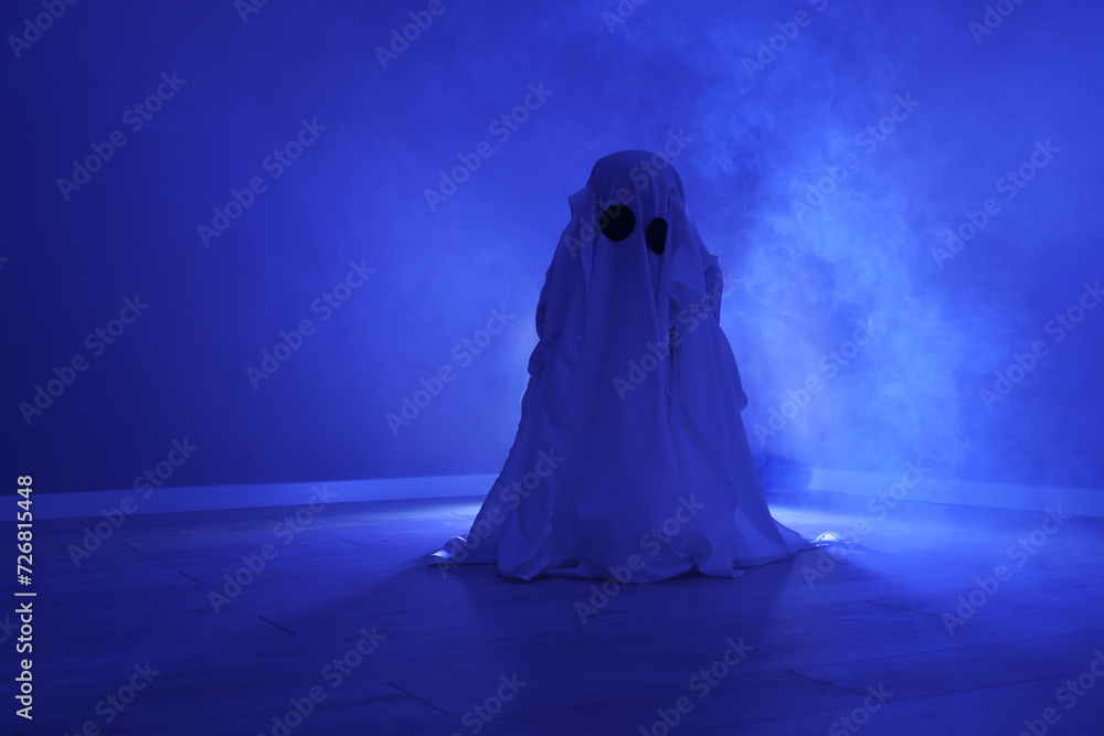 Creepy ghost. Woman covered with sheet in blue light Creepy ghost. Woman covered with sheet in blue light