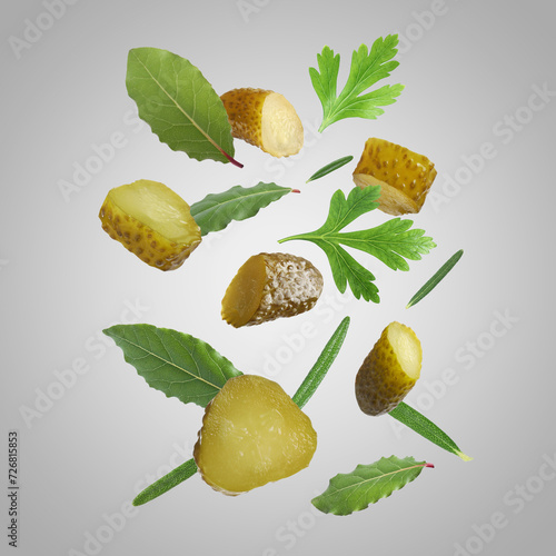 Fototapeta Naklejka Na Ścianę i Meble -  Tasty pickled cucumbers, parsley, rosemary and bay leaves falling on light grey background