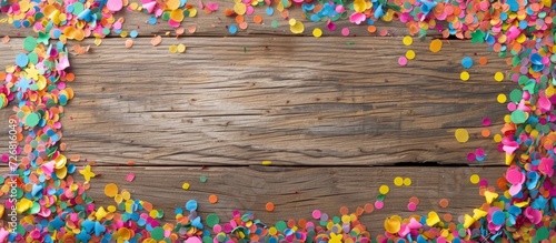 Colorful confetti frame isolated on wooden texture, top view with text space.