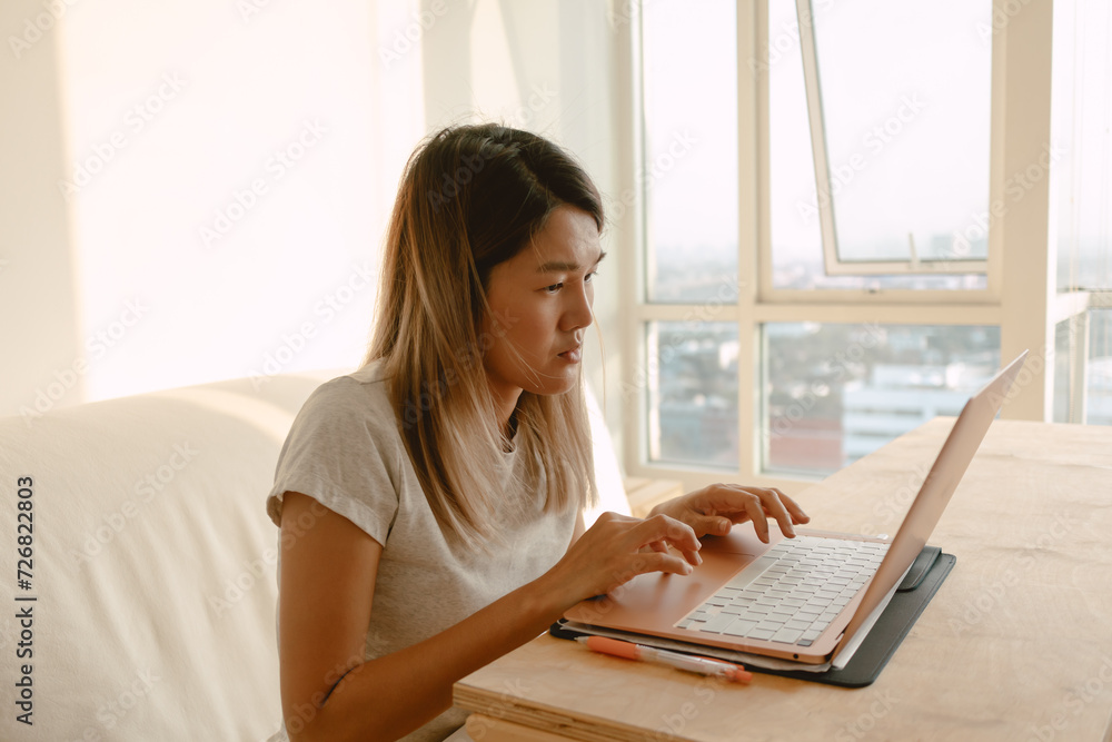 Woman in casual clothes working and typing with her computer laptop in her apartment in concept of work from home Woman in casual clothes working and typing with her computer laptop in her apartment in concept of work from home