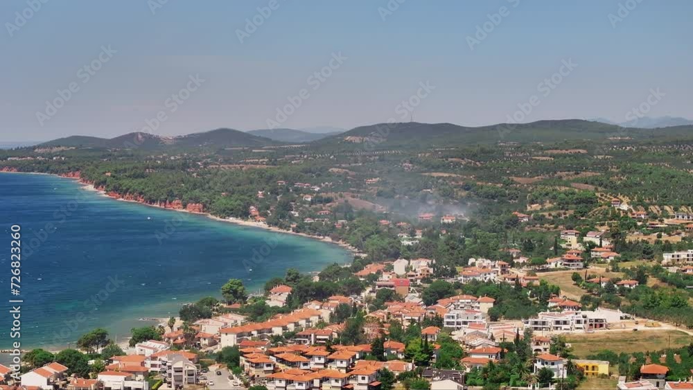 Aerial shot of a drone moving forward over a coastal village, with wisp of smoke from a distant fire visible between the buildings Aerial shot of a drone moving forward over a coastal village, with wisp of smoke from a distant fire visible between the buildings